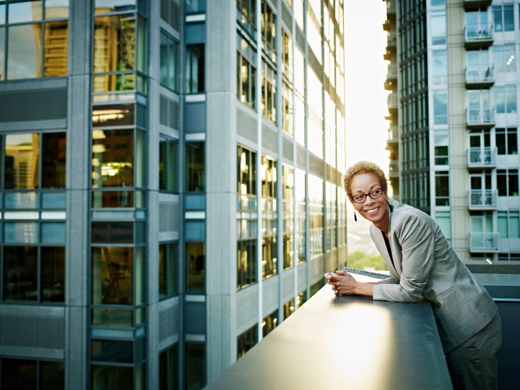 Businesswoman leaning on edge of deck smiling