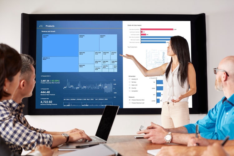 A worker gives a presentation in front of a giant screen