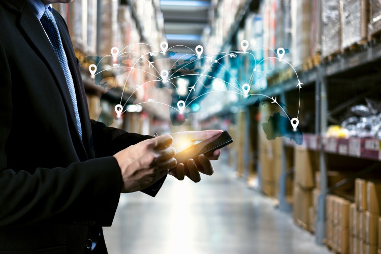Male manager holding a tablet with an augmented reality application animating from the screen in a factory warehouse
