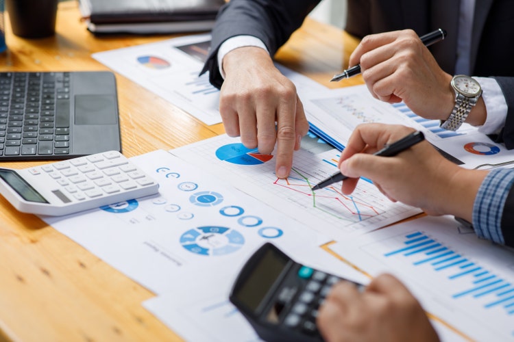 A close up of financial data being reviewed by two business people.