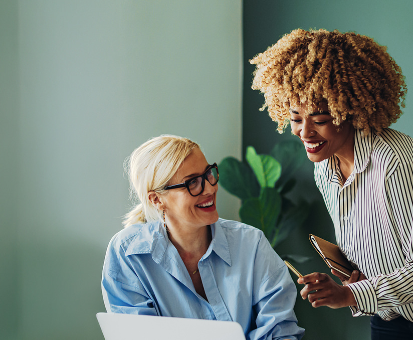 Team of two happy businesswoman working together on a laptop computer - stock photo