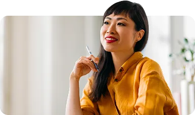 Thoughtful Woman in a Bright Office Space with Pen in Hand - stock photo