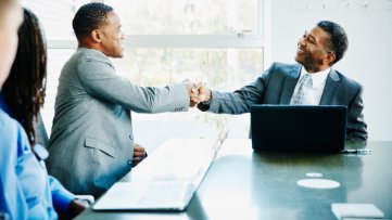 men smiling shaking hands