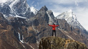 一个人站在山顶,张开双臂拥抱山峦