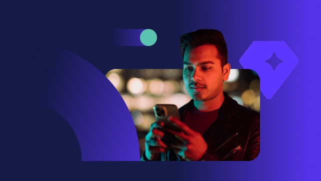 Young and handsome Indian man lit by neon colored lights and using smart phone in city at night.