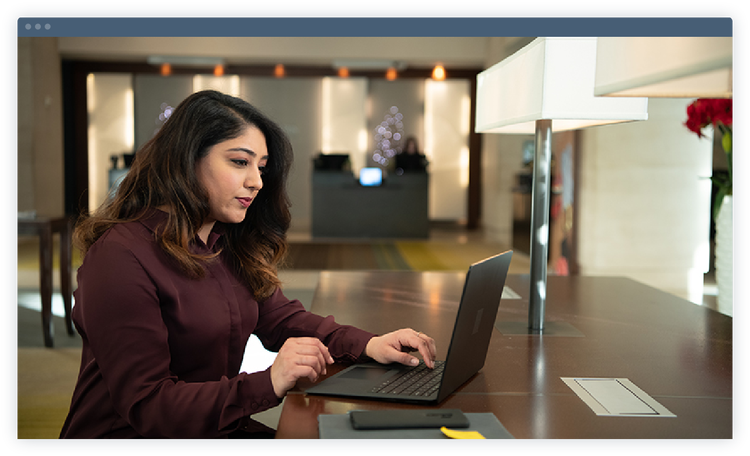 Woman working on laptop in office setting.