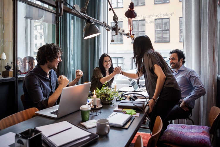 A team of employees bumping fists for accomplishing a goal
