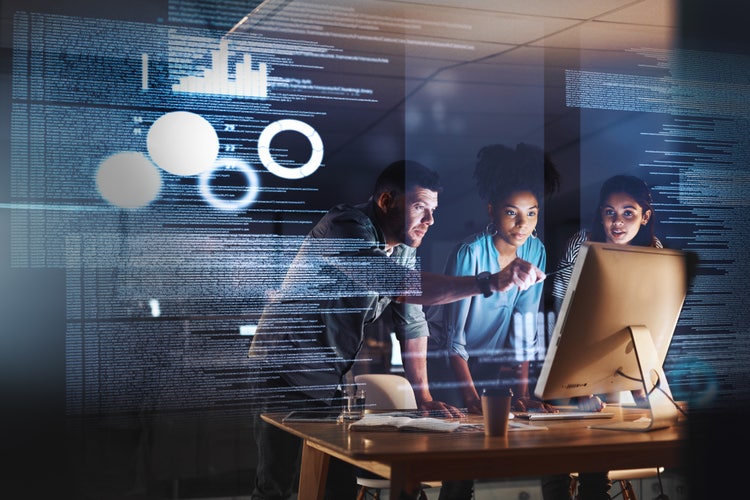 Three coworkers discussing data results on a monitor