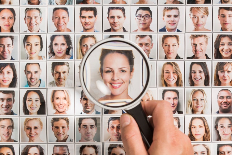 Human resources employee holding magnifying glass on woman portrait amongst others
