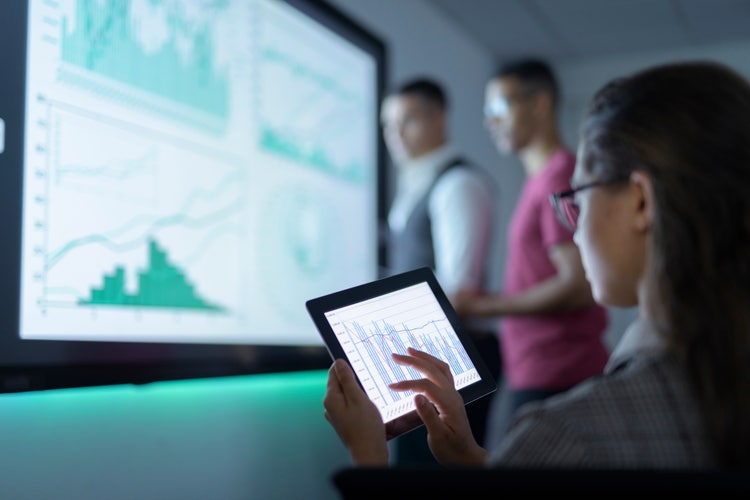 Business people viewing graphs on digital tablet in business meeting