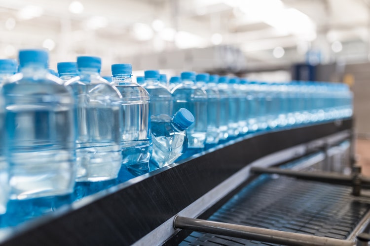Close-up photograph of water bottles moving along an automated factory processing line.